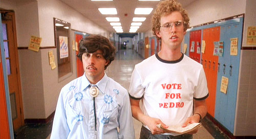 The movie "Napoleon Dynamite", directed by Jared Hess, written by Jared Hess and Jerusha Hess. Seen here from left, Efren Ramirez as Pedro and Jon Heder as Napoleon Dynamite wearing a 'Vote for Pedro' t-shirt. Initial theatrical (limited) release June 11, 2004. Screen capture. © 2004 Twentieth Century Fox. Credit: © 2004 Twentieth Century Fox / Flickr / Courtesy Pikturz. Image intended only for use to help promote the film, in an editorial, non-commercial context.